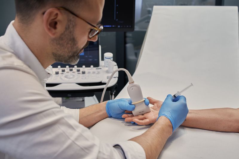 Lekarz radiolog wykonuje zabieg przecięcia troczka palca pod kontrolą USG - leczenie palca trzaskającego w Gabinecie Synovia Warszawa