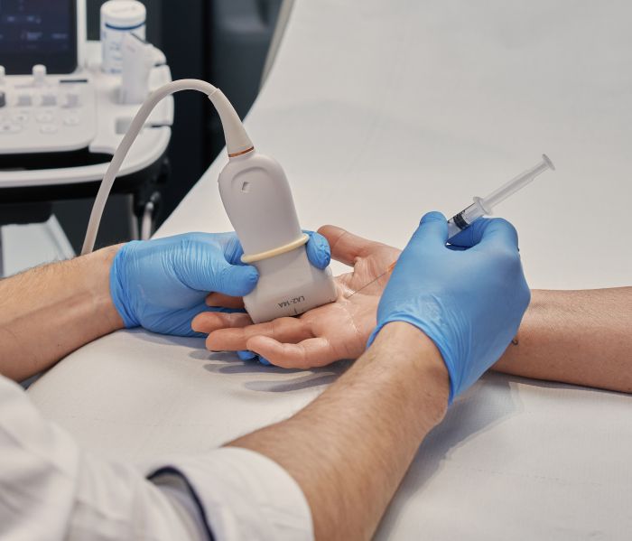 Lekarz radiolog wykonuje zabieg przecięcia troczka pod kontrolą USG w kolanie pacjenta w Gabinecie Synovia Warszawa