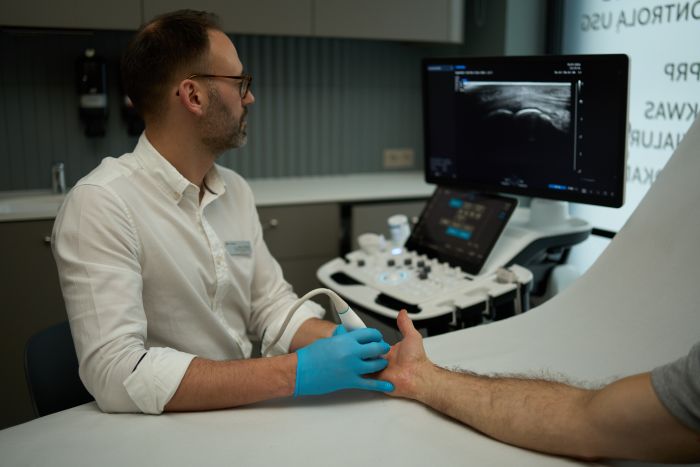 Lekarz wykonujący przecięcie troczka pod kontrolą USG – zabieg ortopedyczny w Synovia Warszawa