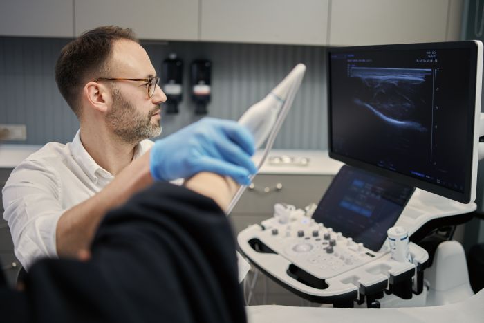 Lekarz wykonujący badanie USG stawu łokciowego w gabinecie Synovia