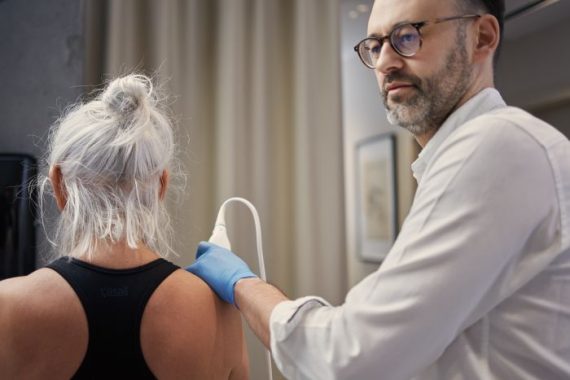 Lekarz wykonujący badanie USG barku pacjentki w gabinecie Synovia Warszawa